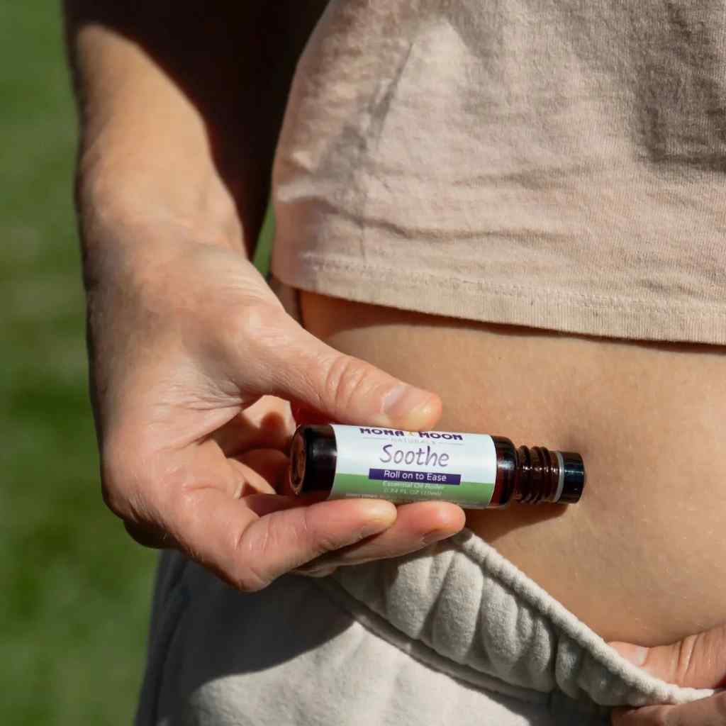 Hand holding a bottle labeled 'Soothe' against a blurred natural background