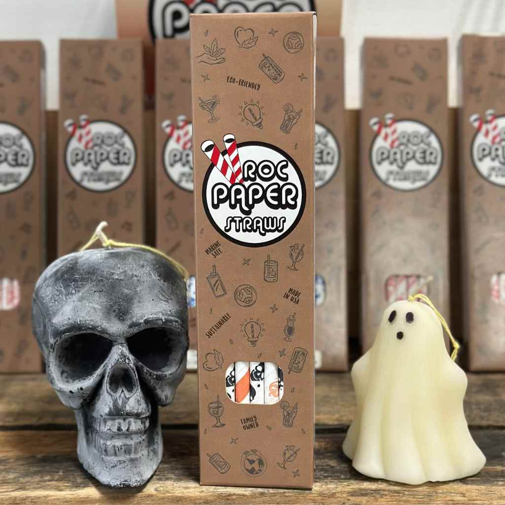 seasonal shot of packaged straws with halloween prints next to halloween candles.