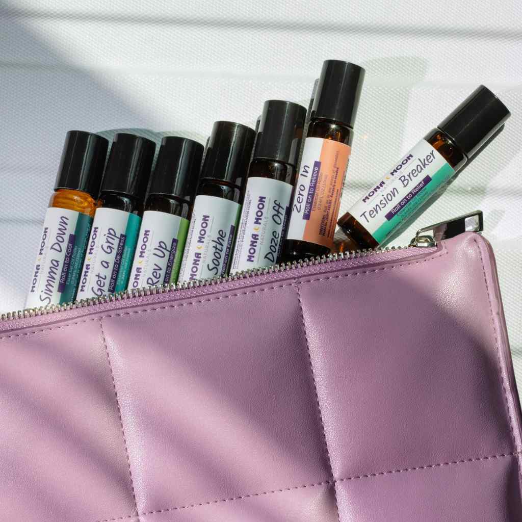 Set of rollerball bottles with labels in a pink pouch on a light background