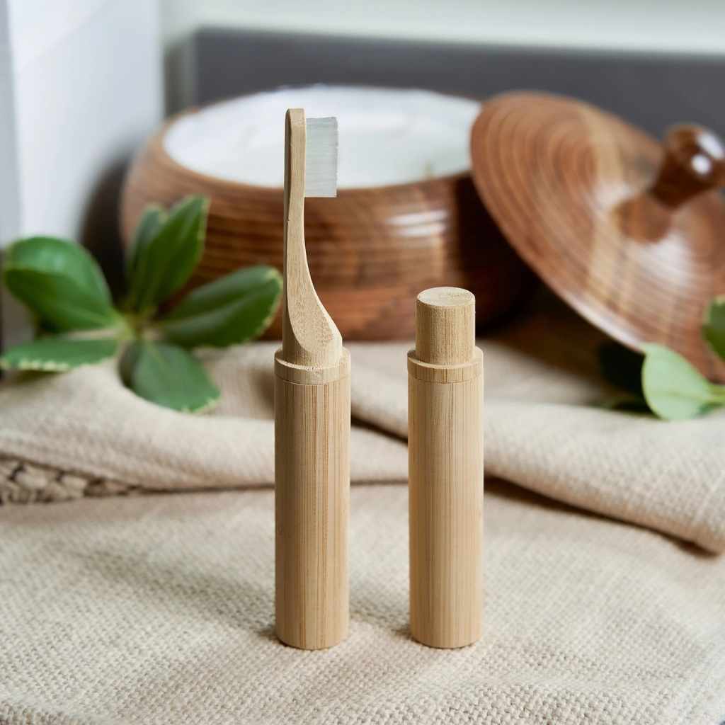 Two bamboo toothbrushes on a textured surface with wooden containers in the background.