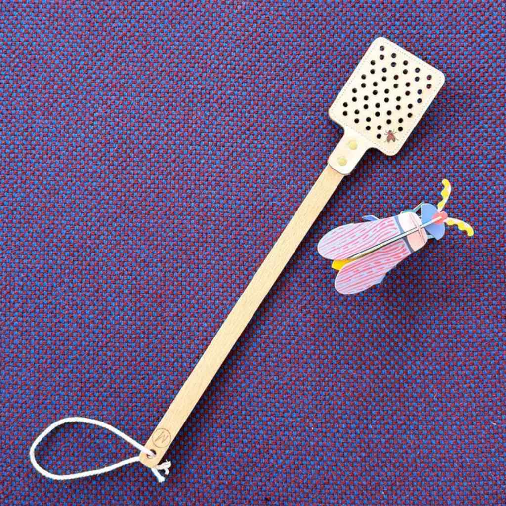 Fly swatter with a cartoon fly on a purple textured background