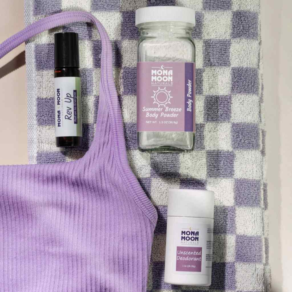 Mona Moon skincare products including a bottle, roller ball, and deodorant stick on a checkered fabric background.
