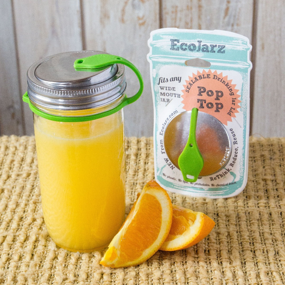 orange juice in mason jar with eco jarz lid and green pop top, orange slices and eco jarz packaging