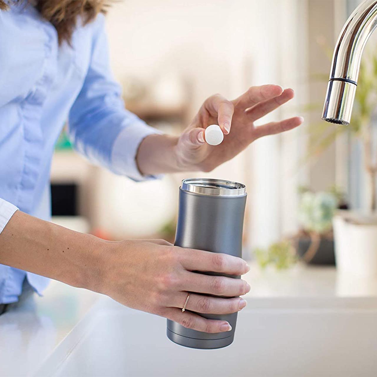 Person dropping cleaning tablet into water bottle