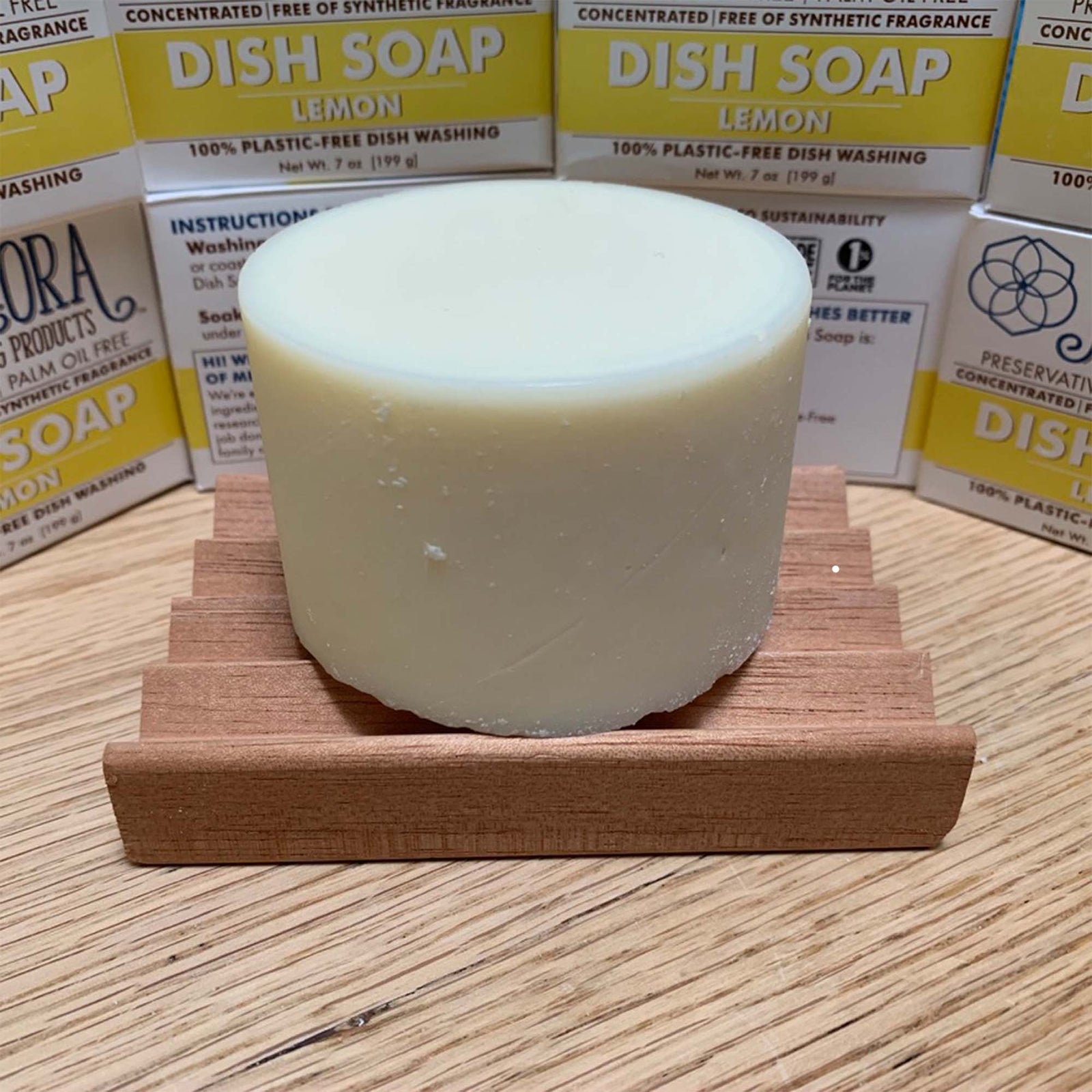 7 oz dish soap cylinder on wood table top, surrounded by meliora dish soap packages