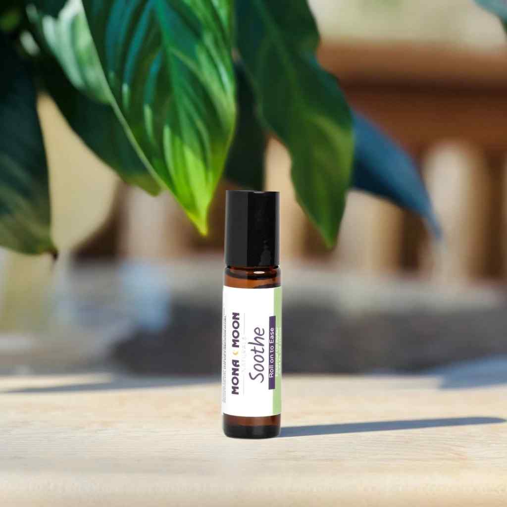 Roll-on bottle labeled 'Mona Moon Soothe' on a wooden surface with a blurred plant in the background
