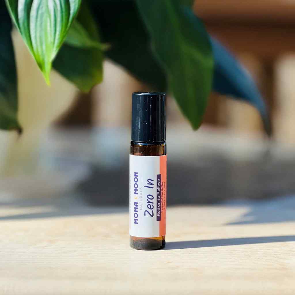 Roll-on bottle labeled 'Zero In' by Mona Moon on a wooden surface with a blurred natural background