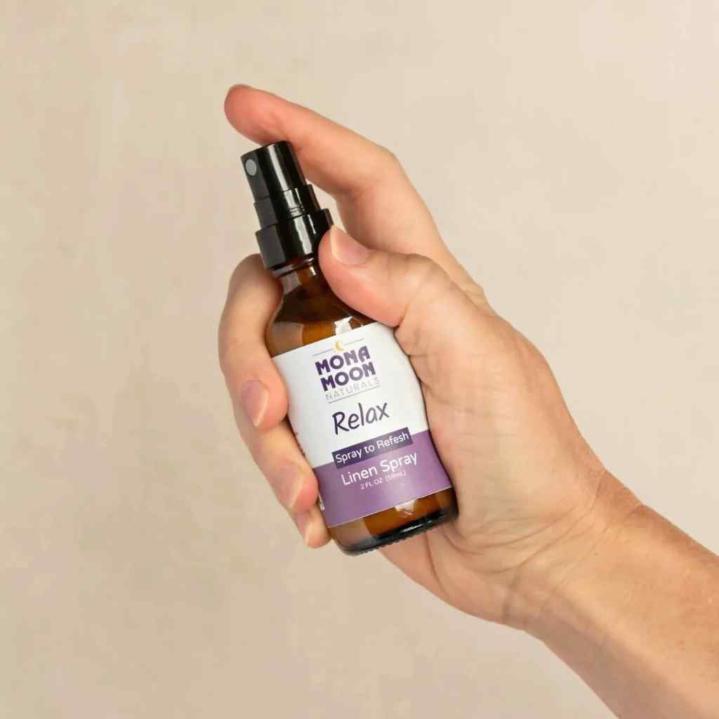 Hand holding a bottle of Mona Moon Relax linen spray against a beige background