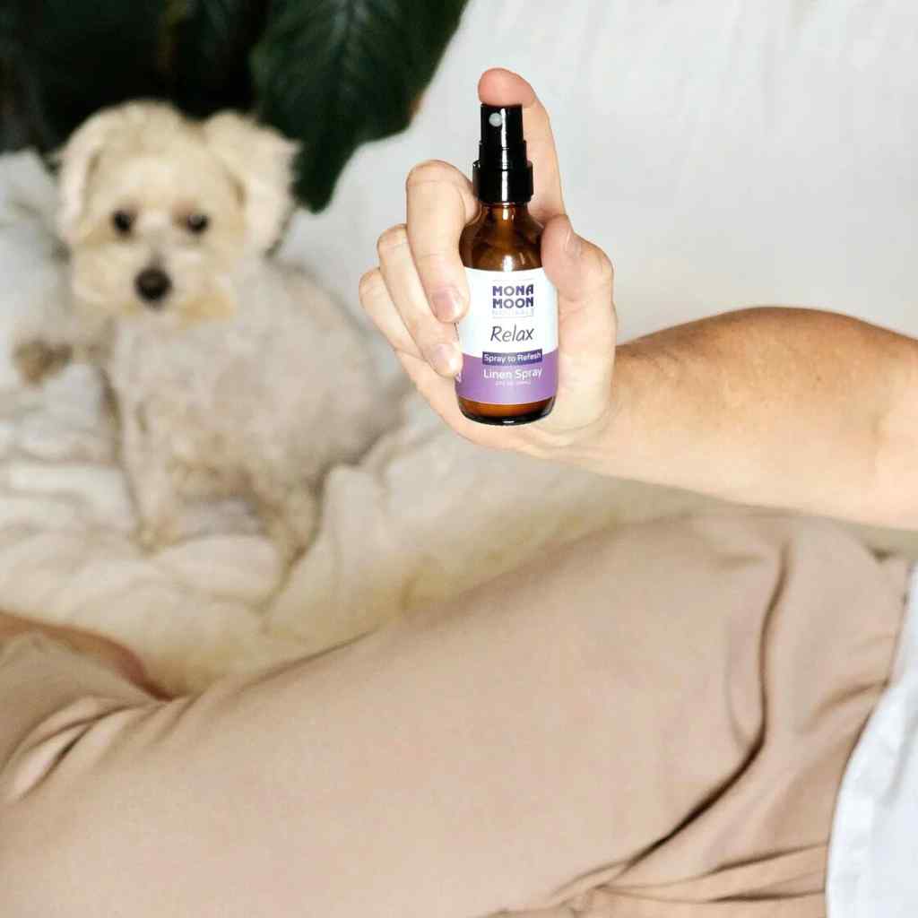 Hand holding a bottle labeled 'Mona Moon Relax' with a dog in the background
