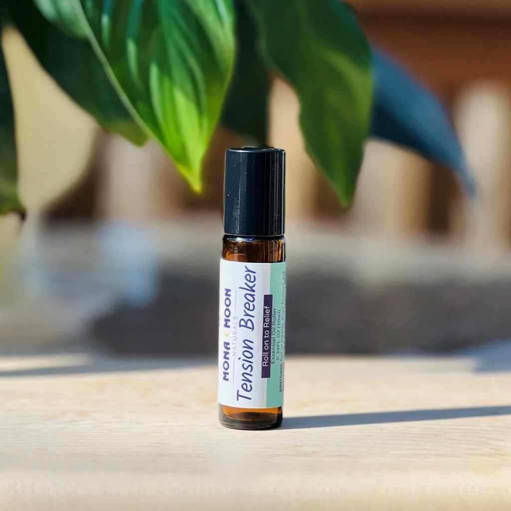 Roll-on bottle labeled 'Tension Breaker' by Moon Moon on a wooden surface with green leaves in the background.