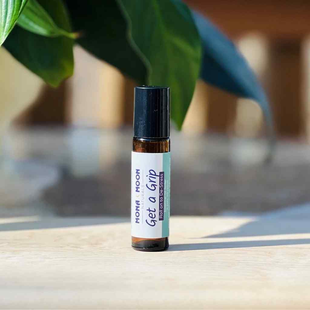 Roll-on bottle labeled 'Get a Grip' by Moon Moth on a wooden surface with a blurred natural background