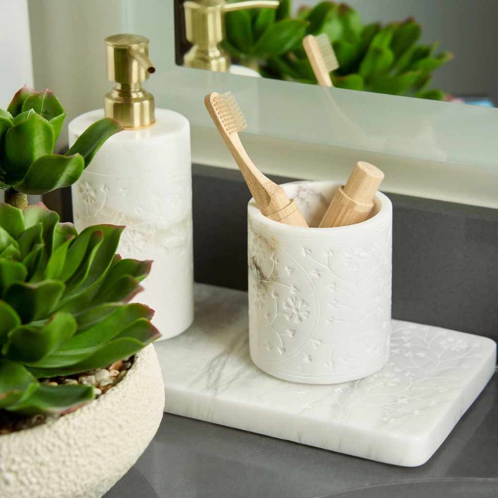 Bathroom counter with white ceramic holder, soap dispenser, and toothbrushes.