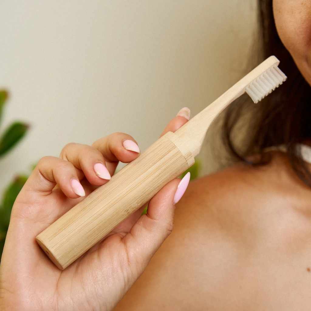 Person holding a bamboo toothbrush with a plain background