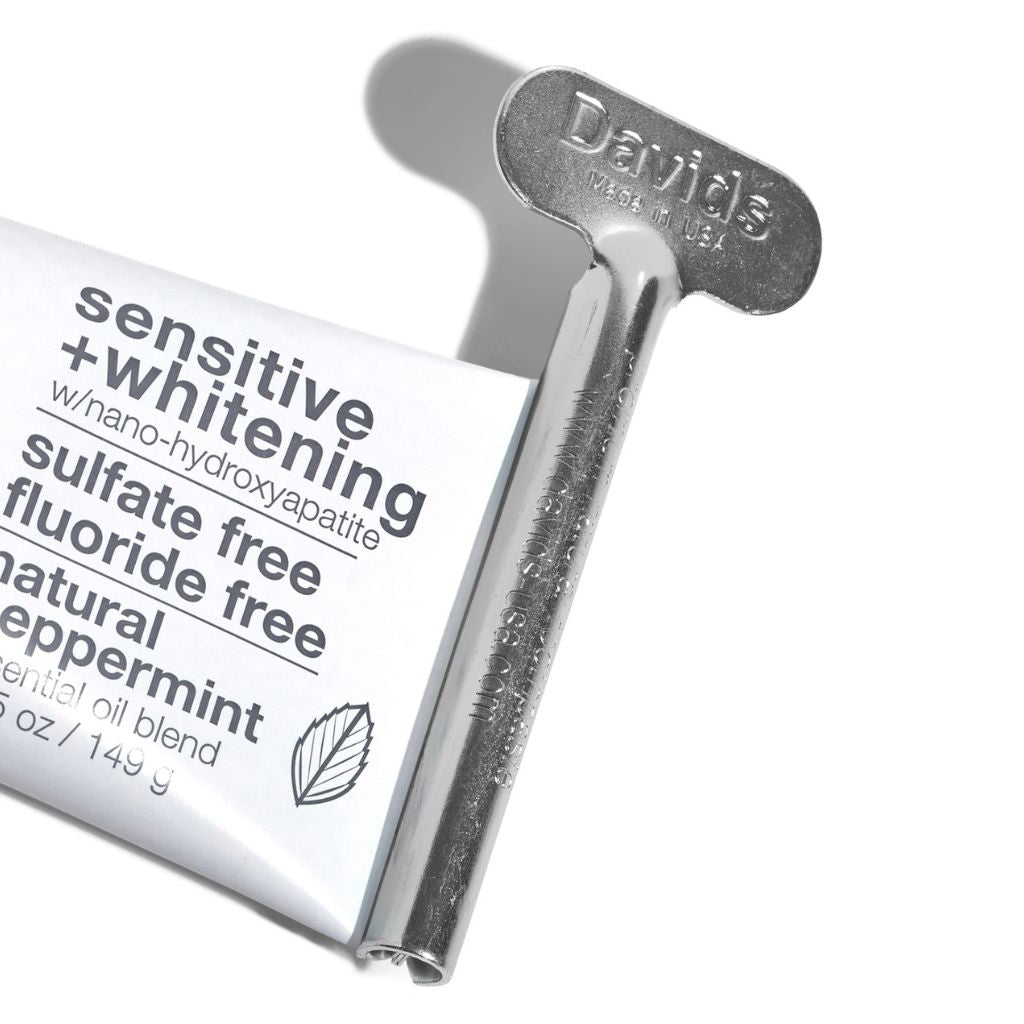 A close-up studio shot of a Davids True Beauty sensitive + whitening toothpaste tube partially pulled from its metallic silver cap, on a clean white background.