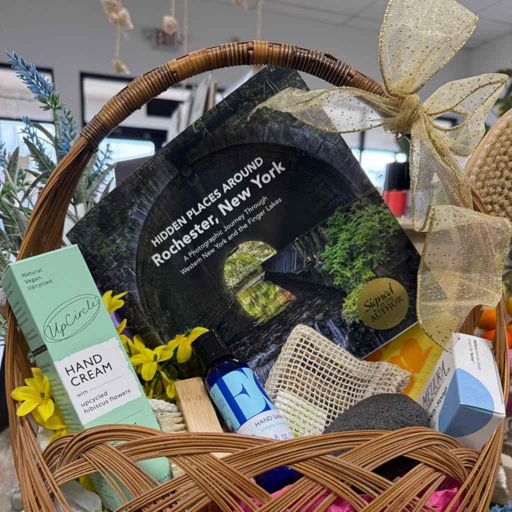 Gift basket with various items including a book titled 'Hidden Places Around Rochester, New York' and a box of Upcircle hand cream.