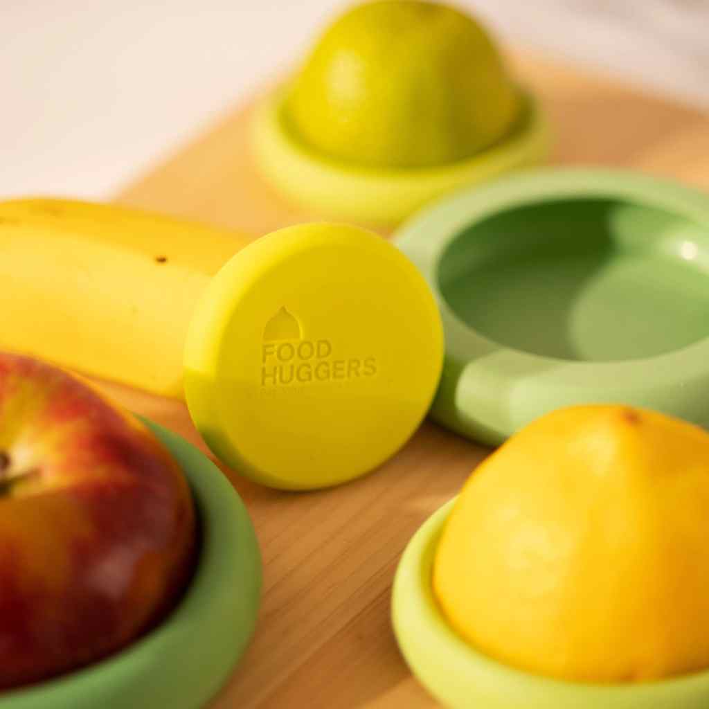 Green silicone food huggers with fruits on a wooden surface