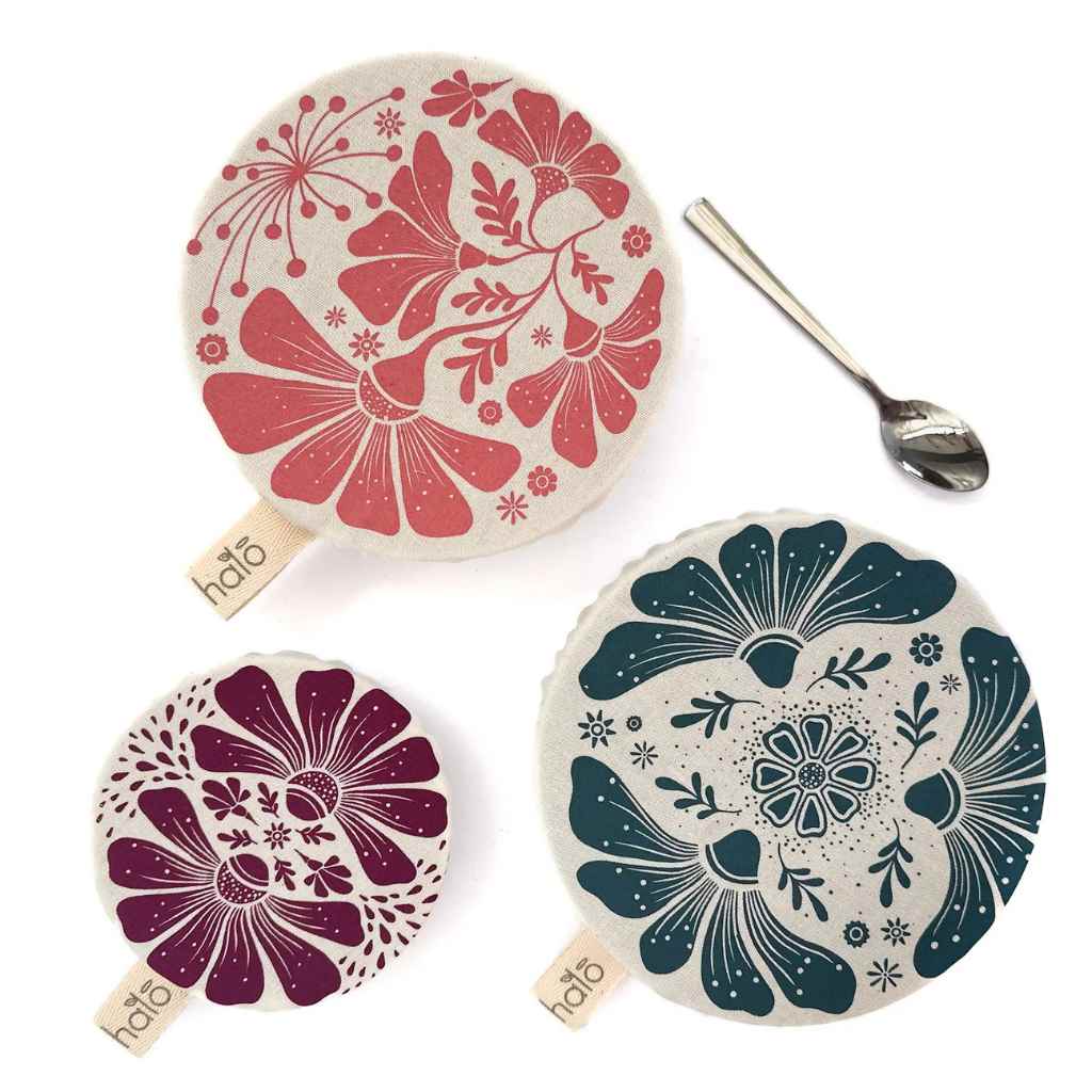 Three floral-patterned bowl covers with a spoon on a white background