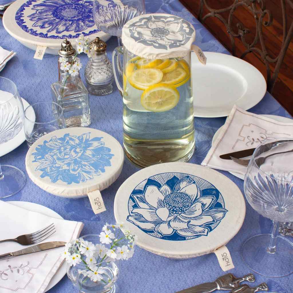 Table setting with blue and white floral dish and jub covers, glasses, and a pitcher of water.