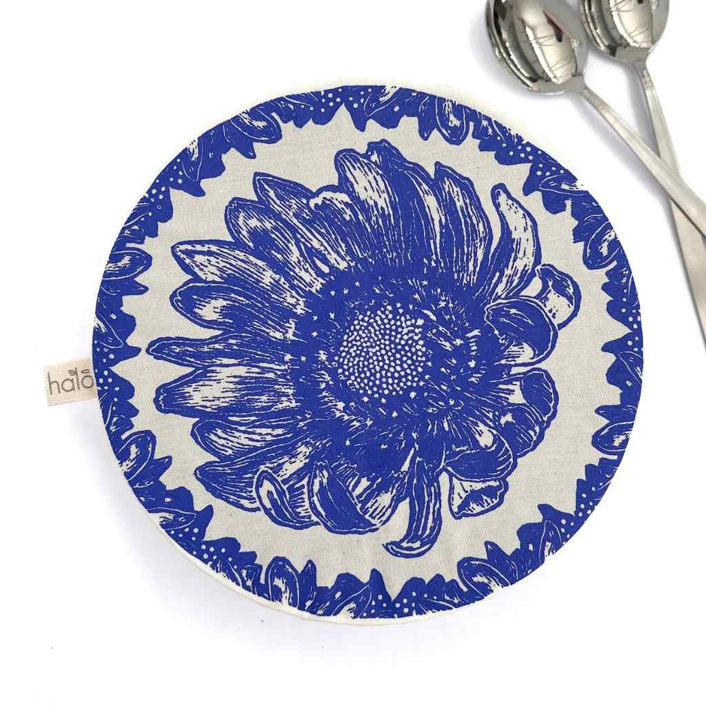 Round blue floral design dish cover on a white background with two silver spoons.