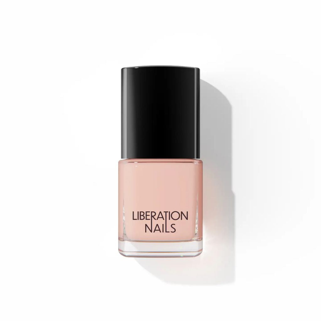 A bottle of Liberation Nails nail polish in a soft peachy pink shade, featuring a glossy black cap and clear glass base, set against a clean white background with a soft shadow.