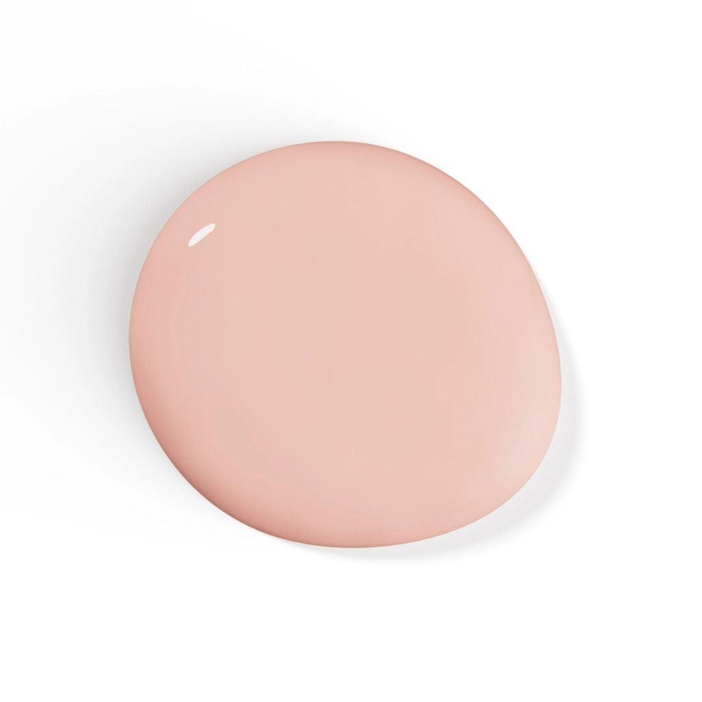 A smooth, glossy, teardrop-shaped swatch of light peach-beige nail polish shown on a clean white background with a soft drop shadow.