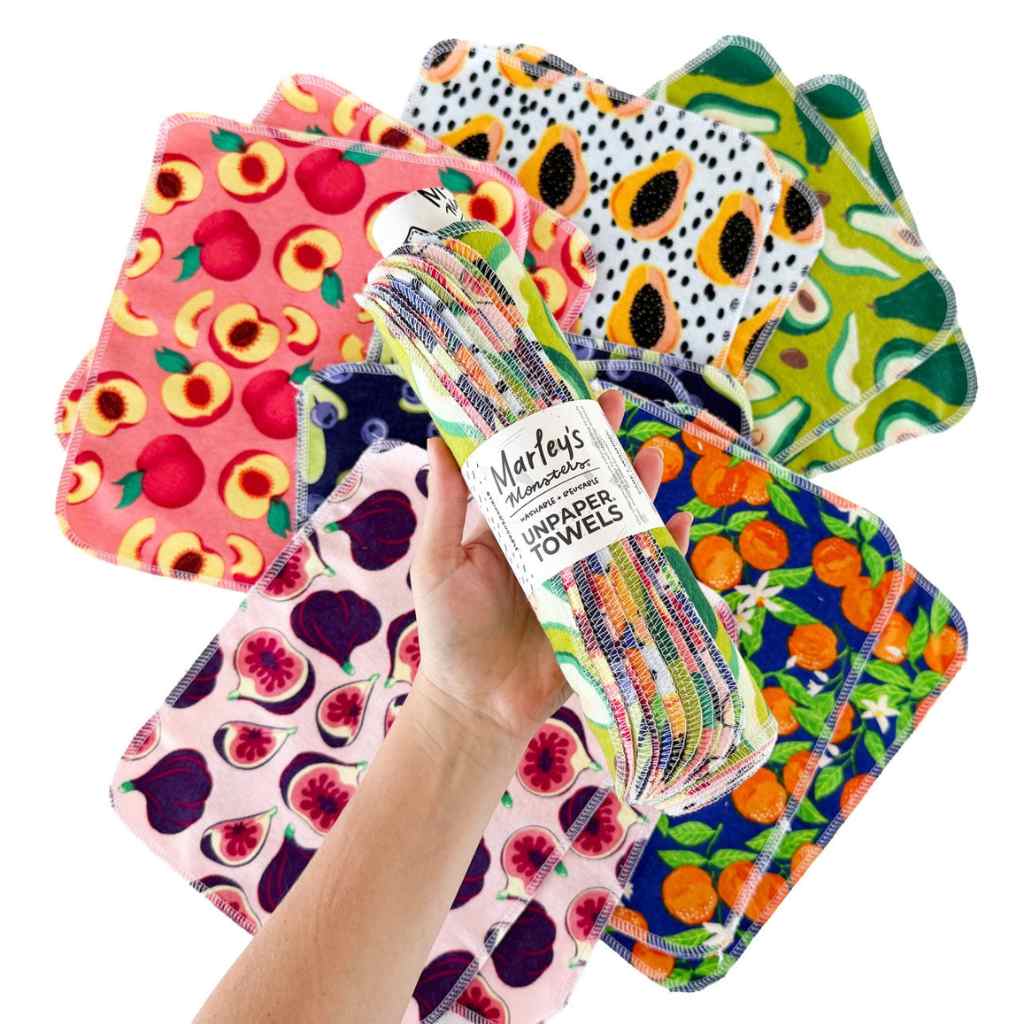 Set of colorful paper towels with fruit patterns held by a hand against a white background