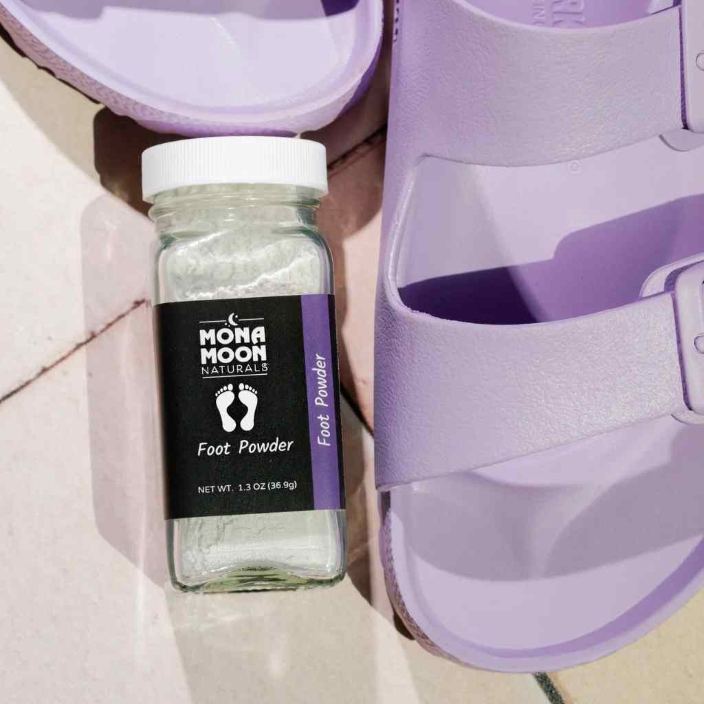 Mona Moon talc-free Foot Powder on floor next to purple birkenstock sandles.