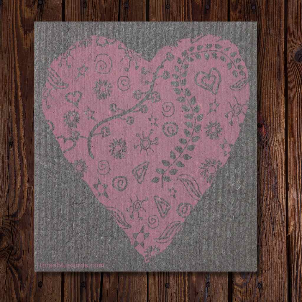 Pink heart-shaped design on a textured gray background, placed on a wooden surface.