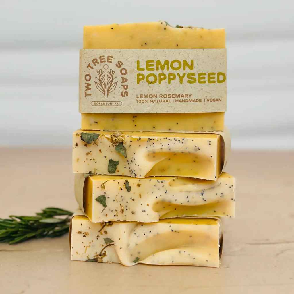 Stack of lemon poppyseed soap bars with 'Two Tree Soaps' packaging on a light background
