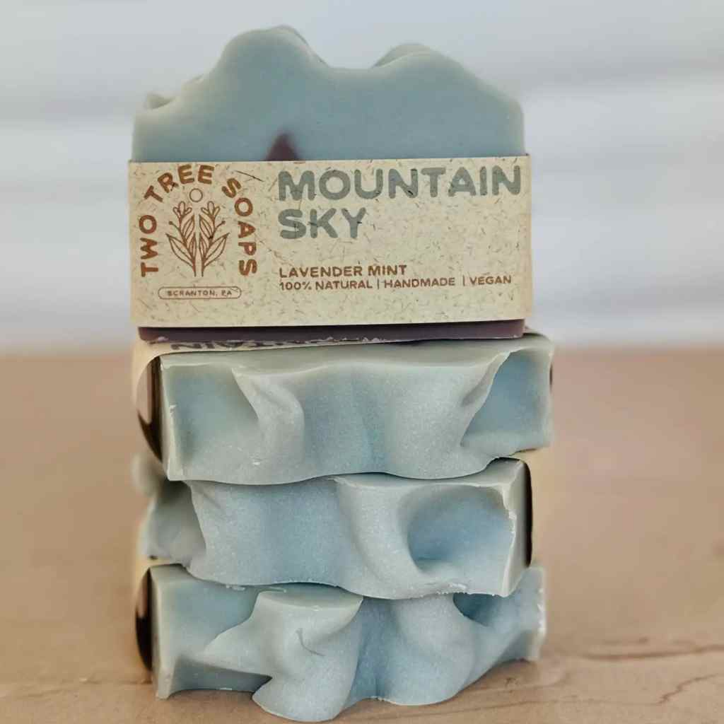 Stack of mountain sky soap bars with a 'Two Tree Soaps' label on a wooden surface.
