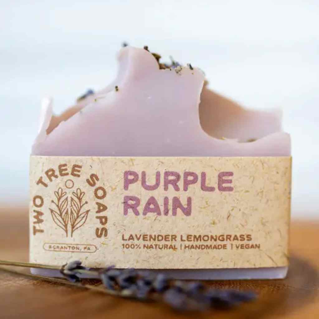 Bar of soap with 'Purple Rain' label from Two Tree Soaps on a wooden surface.