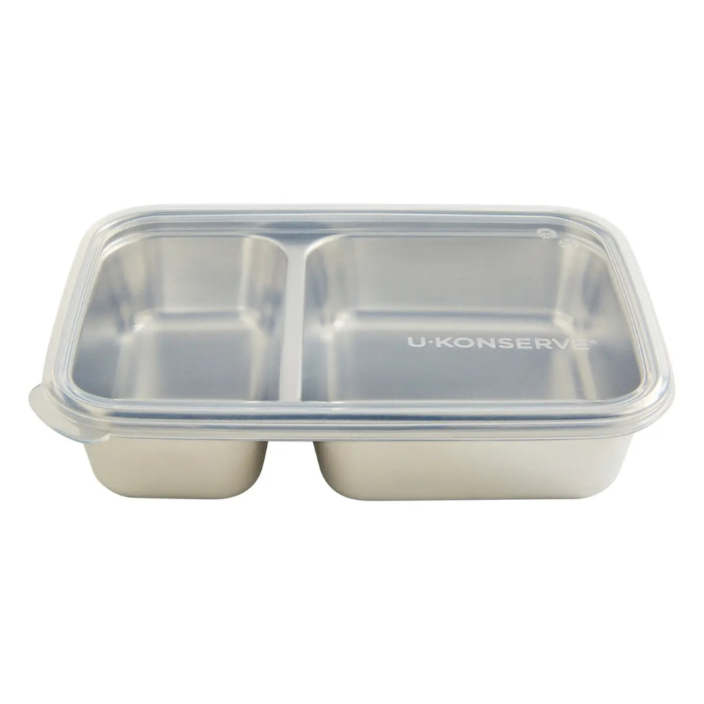A U:KONSERVS stainless steel lunch container with a clear plastic lid and three compartments, shown on a plain white background.