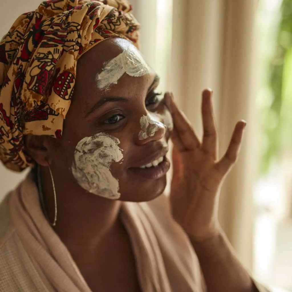 Woman applying face mask to her face with a patterned headscarf