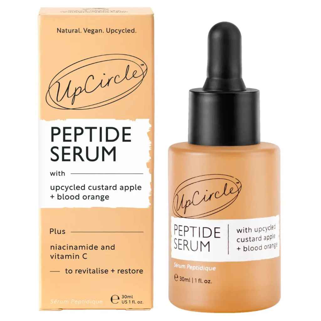 UpCircle Peptide Serum in a 30ml dropper bottle next to its peach-colored packaging box, featuring a black dropper cap and white labels.