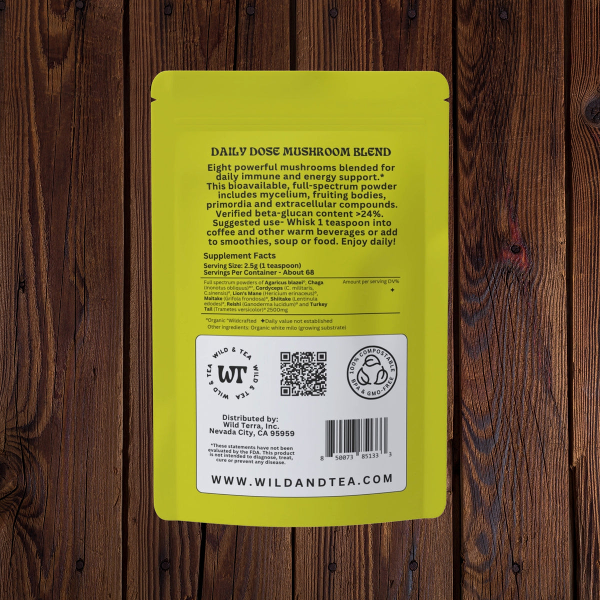 The back of a bright yellow Wild and Tea Daily Dose Mushroom Blend packet, displayed flat against a dark brown wood plank background.