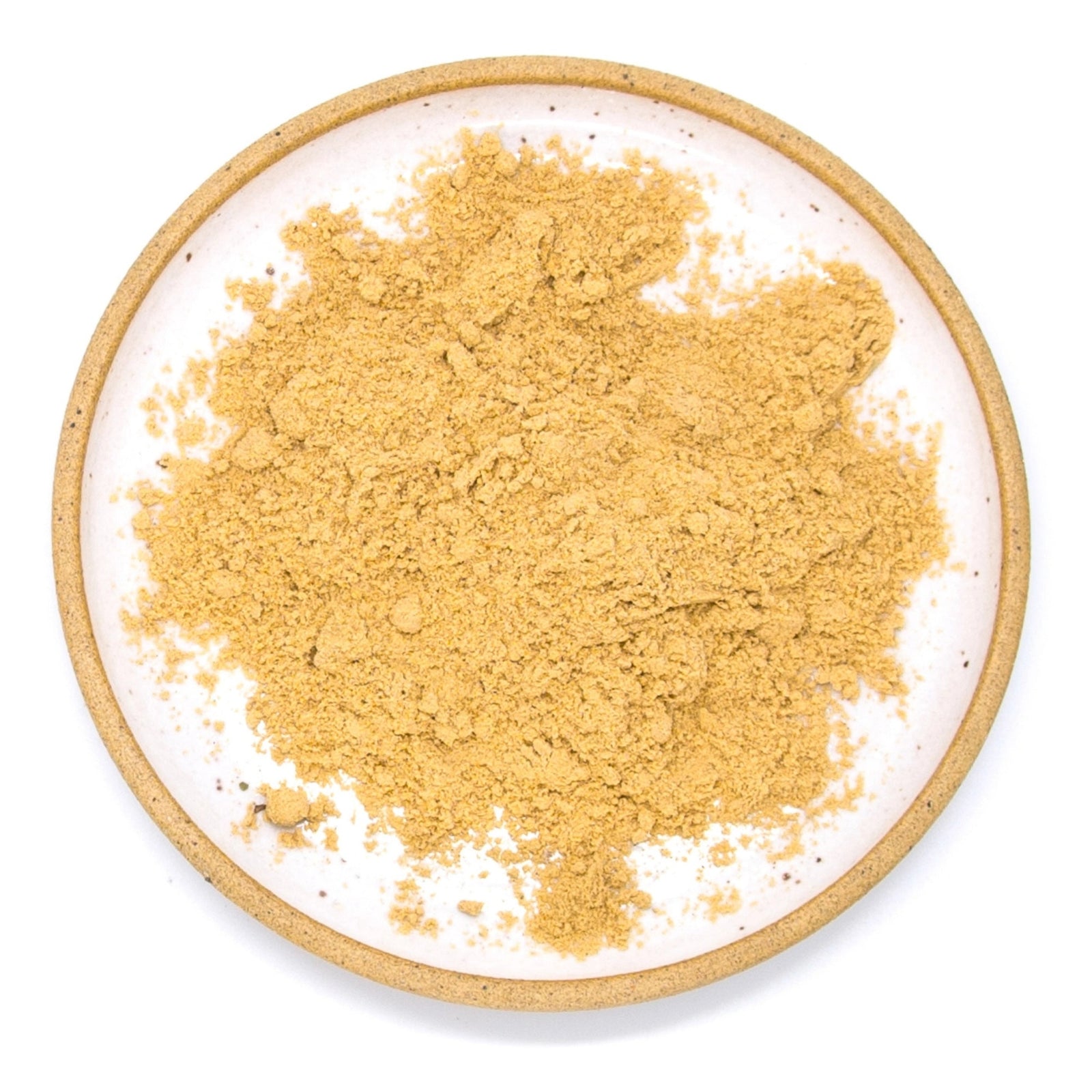 A mound of fine golden-brown powder, likely a spice or herb blend, presented on a speckled white ceramic plate with a natural clay rim against a solid white background.