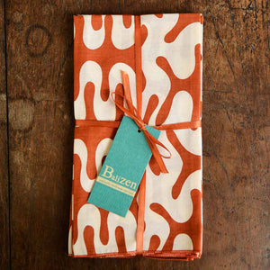 handmade cotton prima napkins with a light swirl design and a vibrant orange background made by Balizen