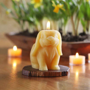 Sculpted beeswax candle in the shape of a Bunny, made by Big Dipper Wax Works. Shown lit among other springtime table decor and candles