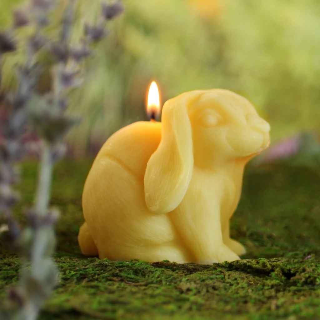 Sculpted beeswax candle in the shape of a Bunny, made by Big Dipper Wax Works. Shown lit.