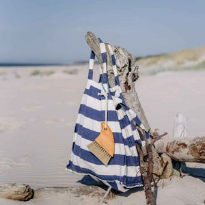 Sand brush for hands and feet - at the beach! Made by Croll & Denecke out of beechwood. Carved into the shape of a shark fin. Shown attached to canvas beach bag with included carabiner.