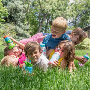 a pile of kids playing in grass each holding their own colorful ecovessel kids insulated water bottle
