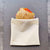 natural cotton fabric sandwich bag with silicone lining made by Food Huggers shown holding a large sandwich