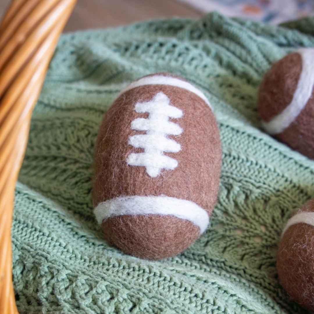 a single Friendsheep "game day" dryer ball (football shaped) on a green blanket