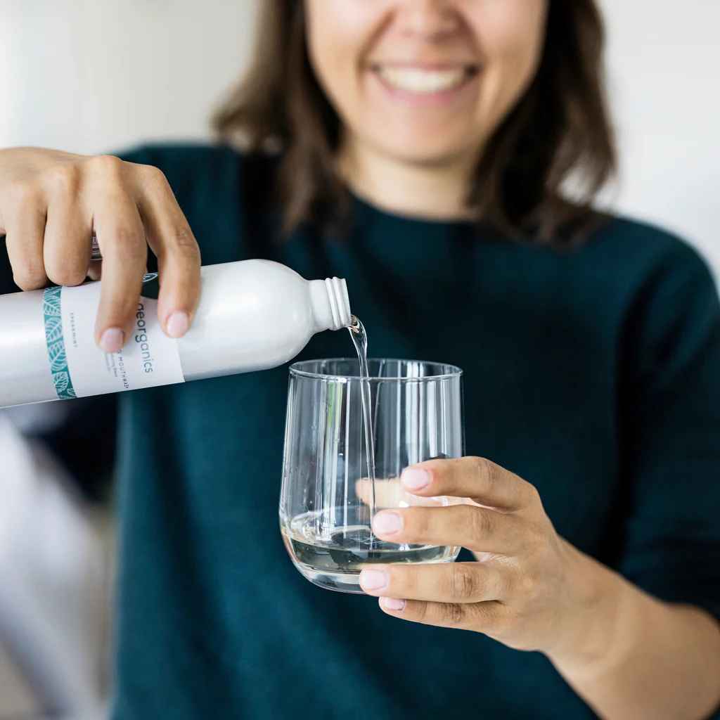 Woman pouring Georganics organic mouthwash into a glass