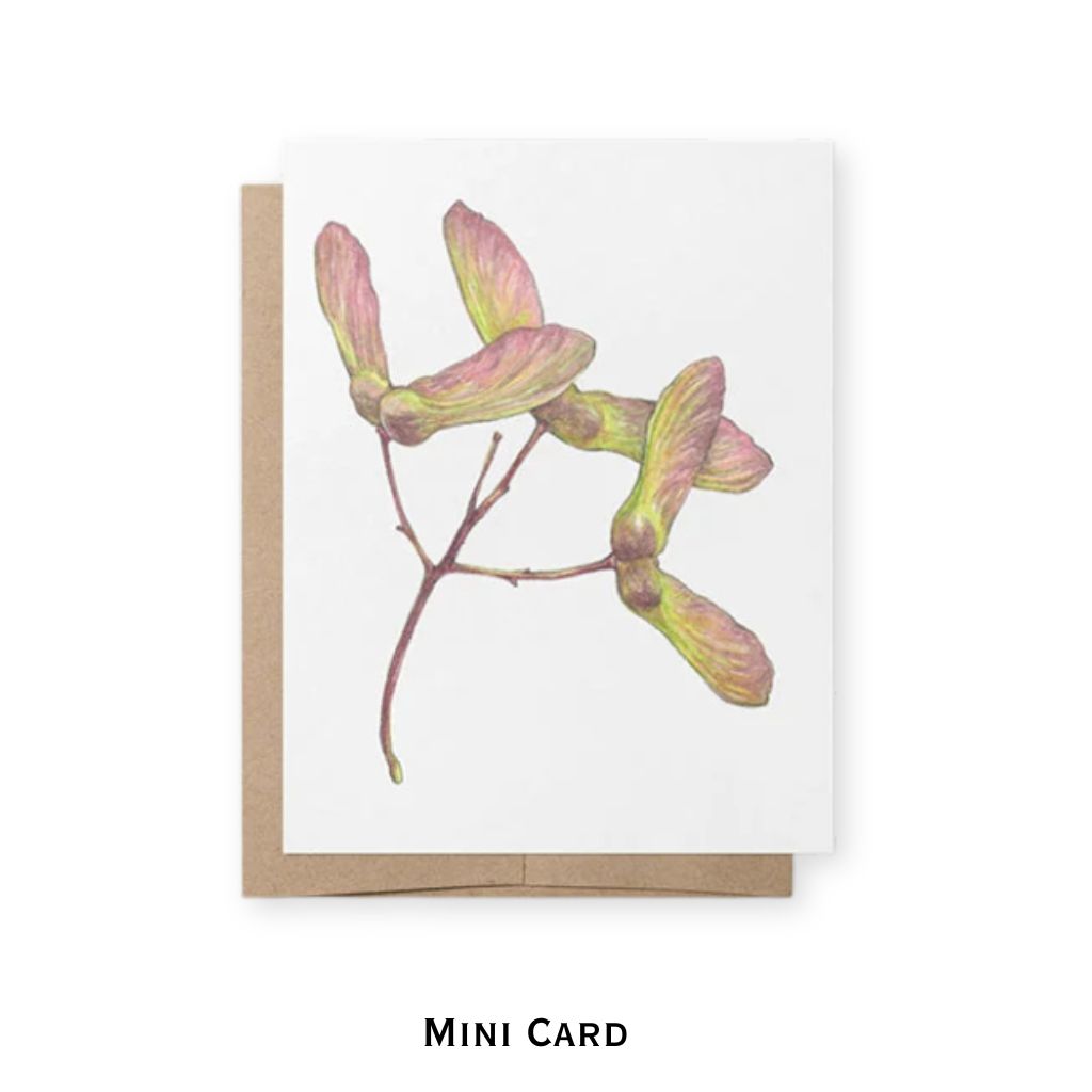 A mini greeting card featuring a watercolor illustration of maple seeds on a white cardstock, shown with a brown kraft envelope behind it on a white background. The text 'MINI CARD' is printed below.
