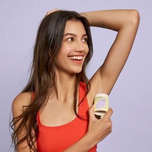 a woman using natural, plastic-free hibar deodorant, smiling