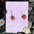 pumpkin dangle earrings on purple card stock sitting on black rocks for display