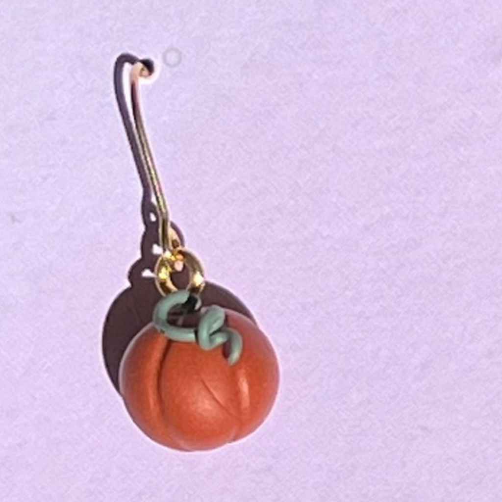 close up of one pumpkin earring on purple backing