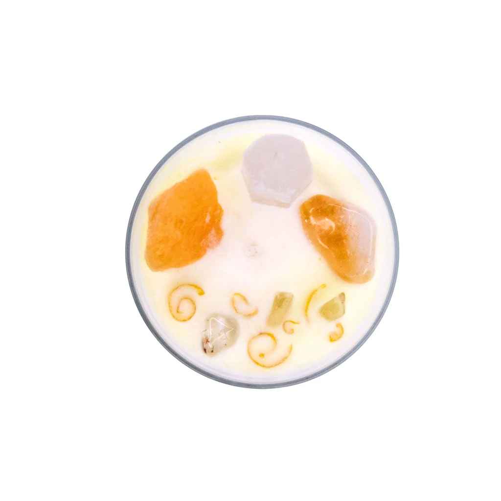 Top view of Crystal Intention Candles | Energy & Abundance - a white soy candle with white and orange crystals and a cotton wick. 