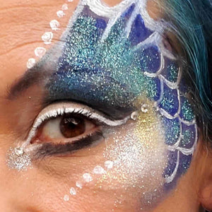 a pilclose up of a woman's face with blue and white face paint and turquoise  glitter applied. Eco-Friendly Glitter made by Natural Earth Paint